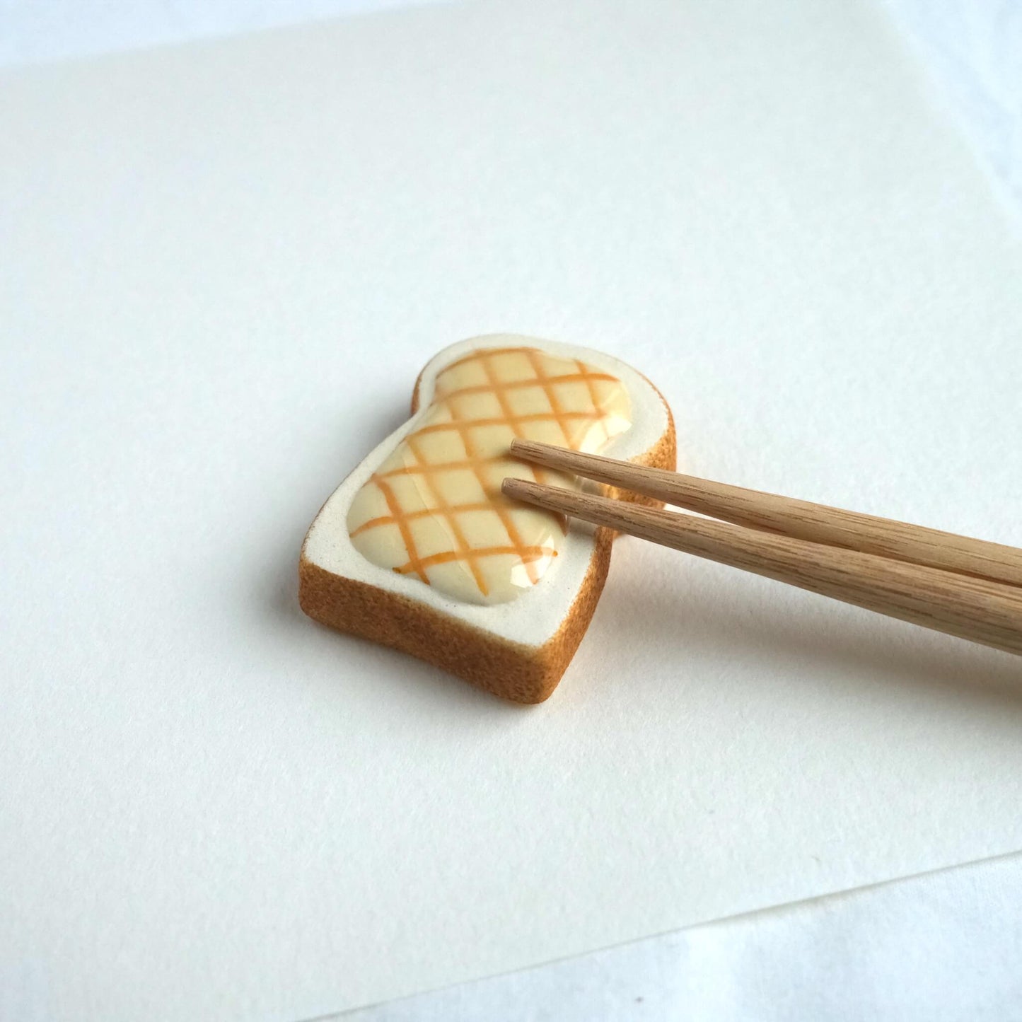 Chopsticks resting on a melon toast chopstick rest.