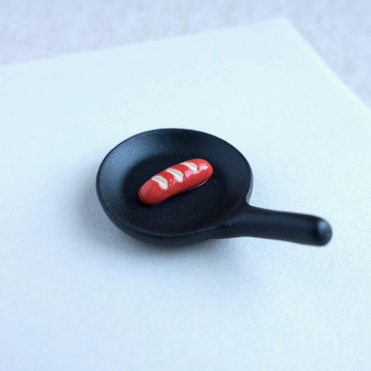 Top view of ceramic fry pan with sausage chopstick rest, adding a touch of Japanese Kawaii charm to your table.
